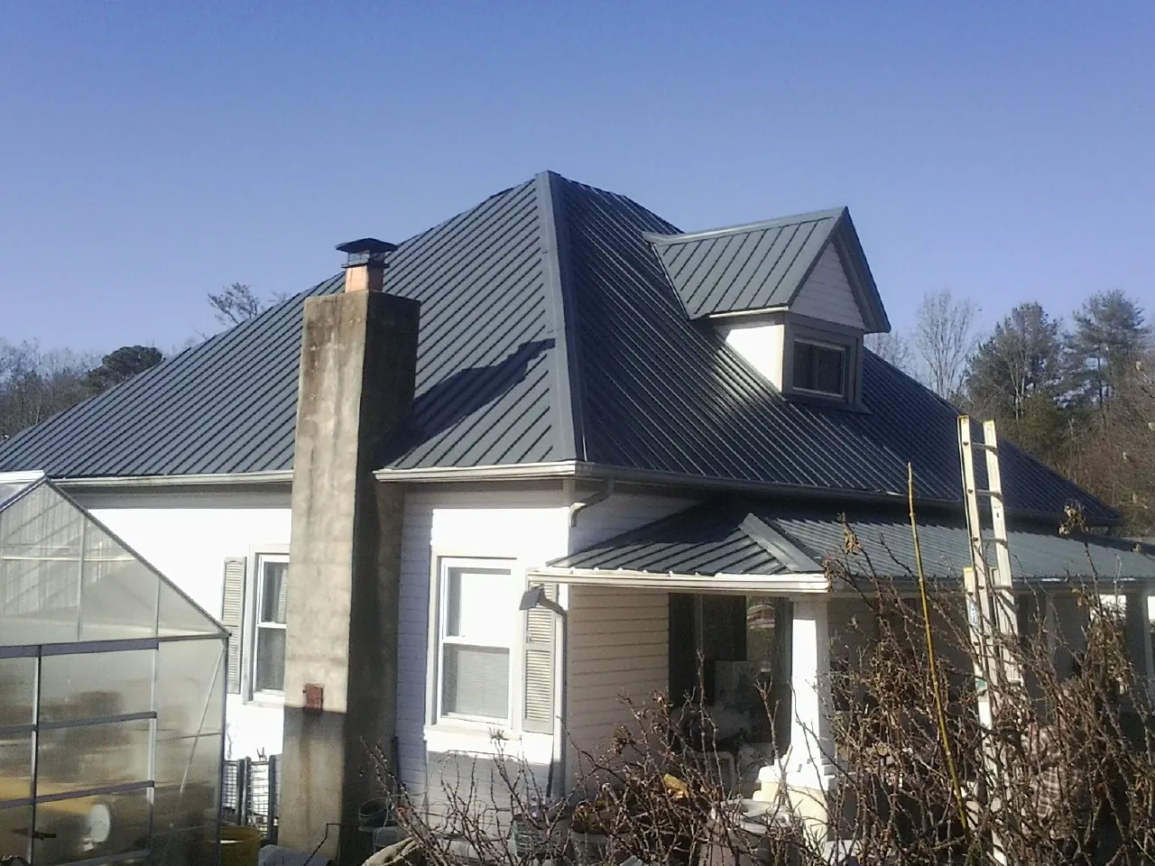 Dark blue standing seam metal roof on a white farmhouse with dormer — Slate & Tile Roof Repair by Roofing Brothers in Nooksack