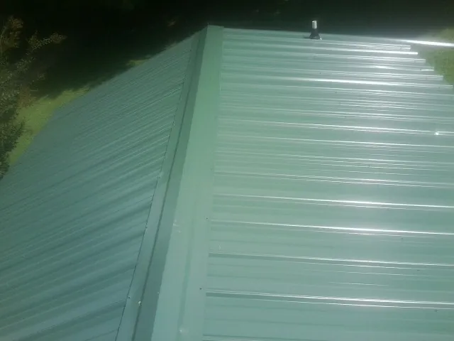 New green metal panels meeting at the ridge of a roof — Flat Roof Repair work by our crew in Nooksack