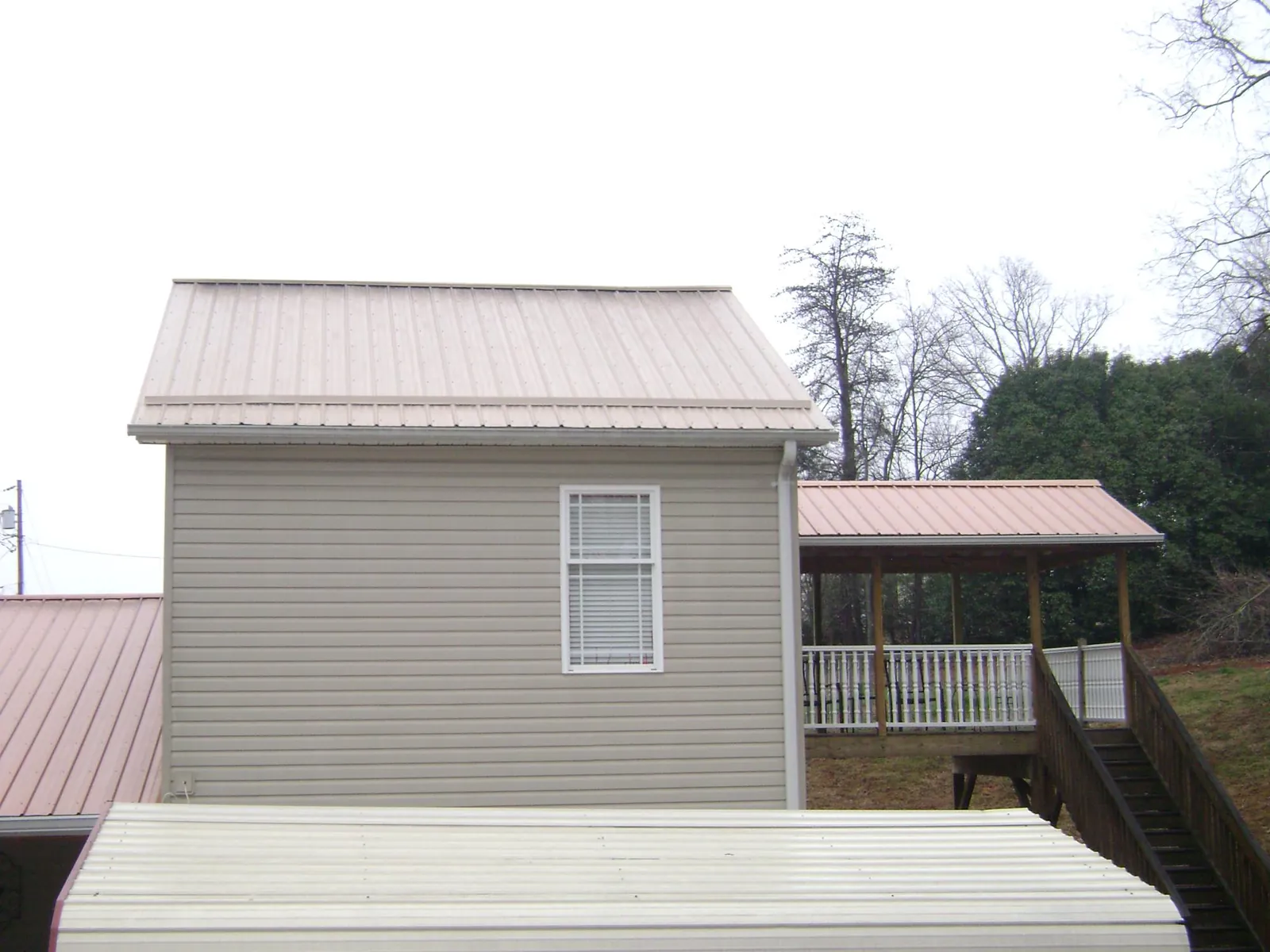 Tan metal roofs on a two story addition and attached porch, from a Roof Replacement job in Nooksack