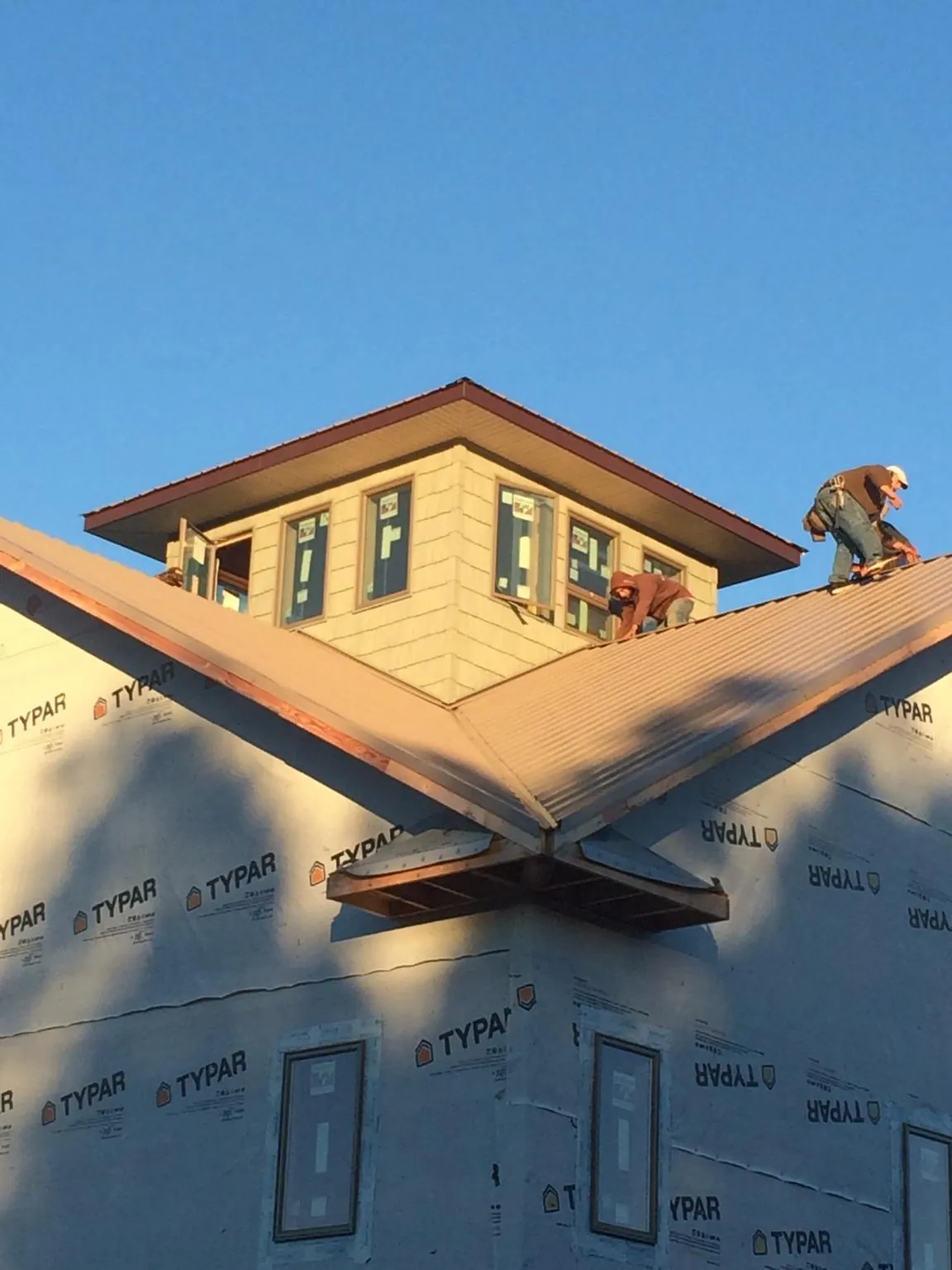 Roofers working around a rooftop cupola on a new metal roof at sunset — Roof Waterproofing in Nooksack by Roofing Brothers